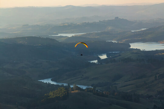 Paraglider voando sobre o rio Lambari no final da tarde - PO&Ccedil;OS DE CALDAS, MG, BRAZIL - JULY 22, 2023: Paraglider flying over the Lambari river in the late afternoon.