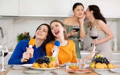 Female participants of friendly feast sing their favorite songs in karaoke and have fun. Two...