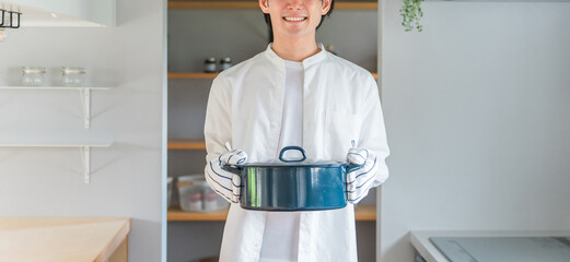 キッチンで鍋を持つ若い男性・料理好きな夫・主夫・料理男子
