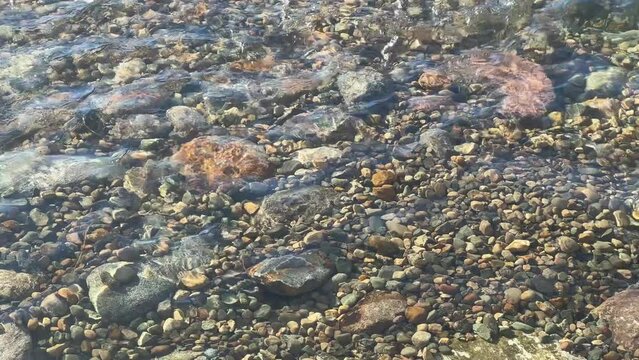 Closeup of crystal clear water rippling over rocky river bed