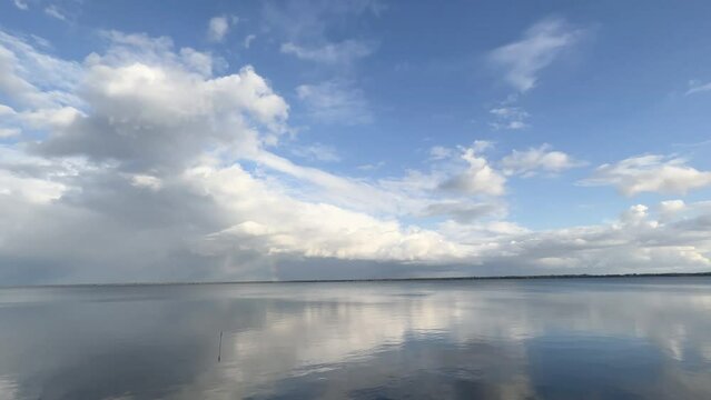 Dramatic white clouds form over a large placid lake in summer