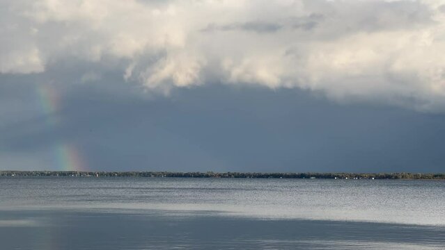 Dark storm clouds over a large lake with rainbow