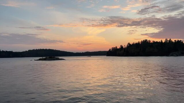 Lake water reflects a soft sunset near silhouetted forest
