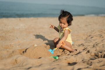 happy toddler baby girl playing sand toy on sea beach