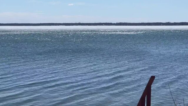 Lake reflections shimmer like diamonds with late winter ice in the background