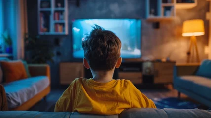 Fotobehang Child Watching TV in a Cozy Room at Night - A young viewer is engrossed in a television show, comfortably seated in a homey, dimly lit living room. © Tida