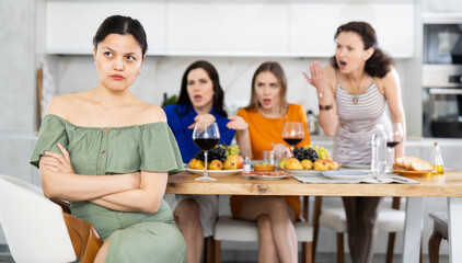 At home party, young Asian woman appearing offended and upset during argument while female friends in background showing disapproval and discontent.. - obrazy, fototapety, plakaty