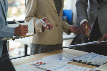 Group of business people meeting, discussion, brainstorming, pointing at graphs and charts to...