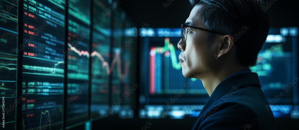Poster a man wearing eyeglasses is focused on examining a massive display of data on a digital screen