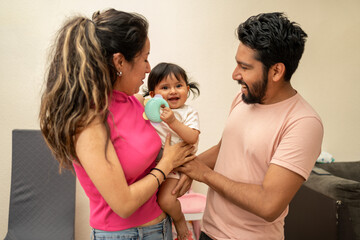 hispanic family having fun in the living room, young latin couple with a baby girl toddler