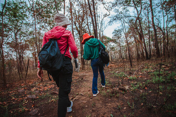 Young woman carries a bag and travels in the natural forest With the morning sun shining concept of tourism
