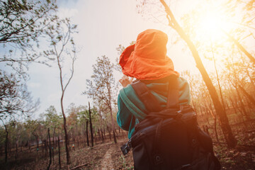 Young woman carries a bag and travels in the natural forest With the morning sun shining concept of...
