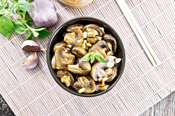 Champignons with oregano and nuts in bowl on bamboo napkin top