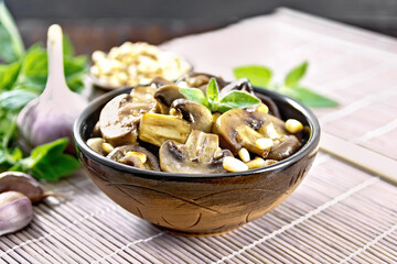 Champignons with oregano and nuts in bowl on dark board