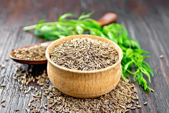 Cumin seeds in bowl and spoon with herbs on board