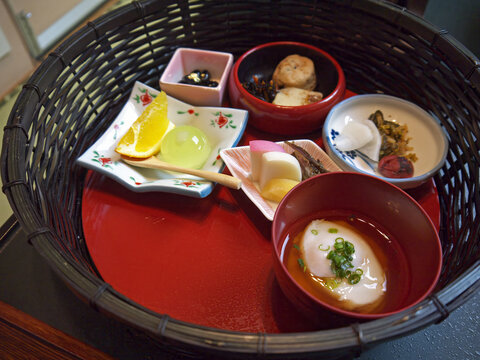 Traditional japanese ryokan breakfast set with poached egg, tsukemono pickled vegetables and fruits in round wicker tray