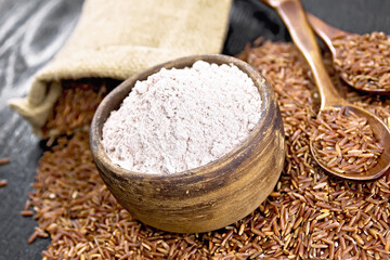 Flour red rice in bowl on dark wooden board