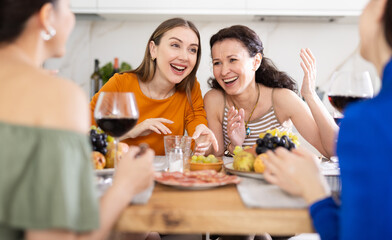 Happy women congregated around a festive table; participating in animated discussions and enjoying...
