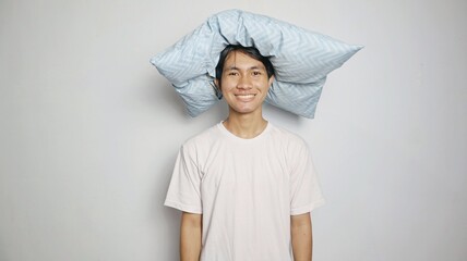 Young smiling Asian man posing putting pillow over his head