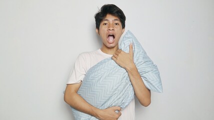 Shocked Asian young man posing hugging a pillow