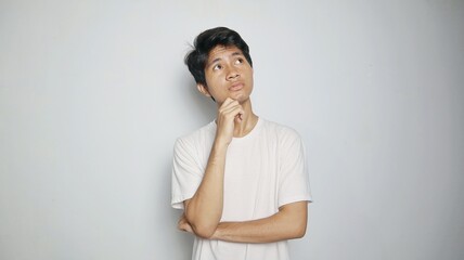 Young Asian man thinking while looking up and hand holding chin