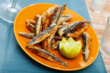 Fried anchovies with lemon on a plate closeup