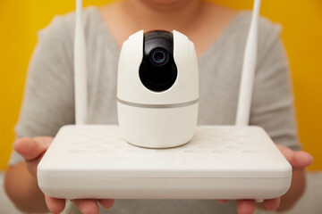 Two hands present an Internet Router and Wireless security camera onto the camera 