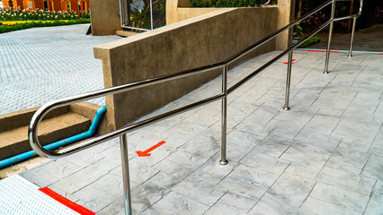 In and out pedestrian way at entrance gate with arrow sign and metal handrail separate.