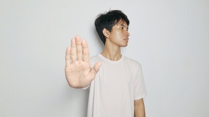 young asian man in white shirt gesturing to say no or refuse or block or stop