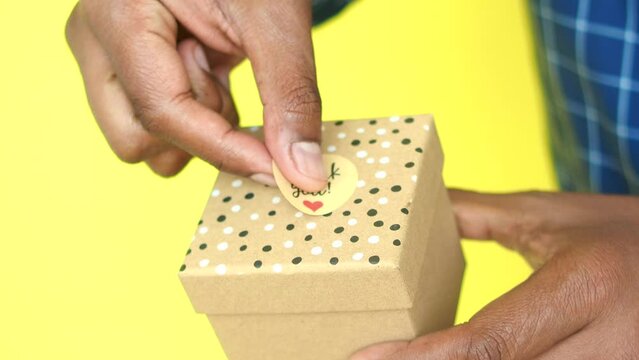  hand putting a thank you sticker on a gift box 