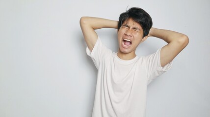 Young Asian man in white shirt gesturing with hand holding head, feeling dizzy, sick, stressed,...
