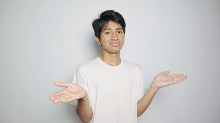 Young Asian man in white shirt gesturing with open arms as if he doesn't know