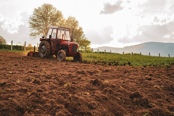 Farmer in tractor sowing crops at agricultural fields in spring.