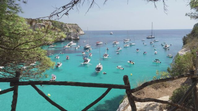 Many boats moored offshore in Cala Macarella cove of Menorca Island, Spain