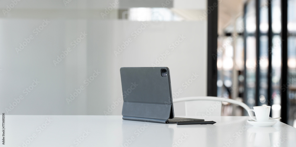 Poster rear view of digital tablet with keyboard on white table in cafe.