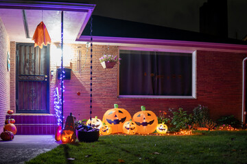 House porch decorated for Halloween with orange inflatable pumpkins and purple garlands