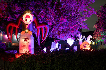 Glowing Halloween outdoor decorations - inflatable vulture sitting on a gravestone, ghosts and pumpkins in purple light