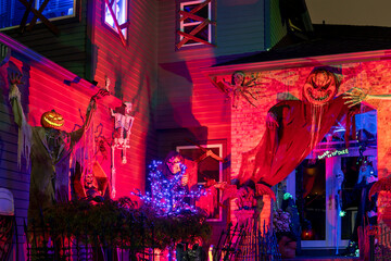 Scary Halloween house night outdoor decorations of monsters near the house in red and purple light
