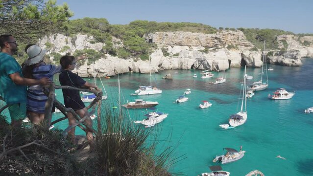 Family with kids admiring the panorama of Cala Macarella in Menorca, Spain