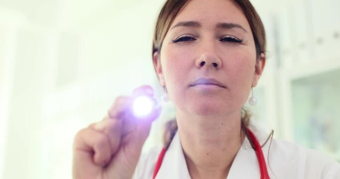Ophthalmologist examines patient eyes with flashlight