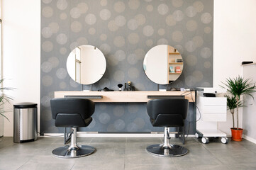 A hair salon with two chairs and two mirrors