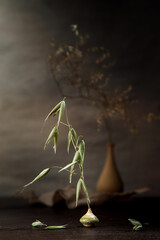 Modern still life with dry grass in a clay vase on a dark background