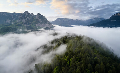 Misty Mountain Landscape with Clouds: A serene scene of fog veiling the majestic peaks, creating an ethereal atmosphere in this mountain landscape.