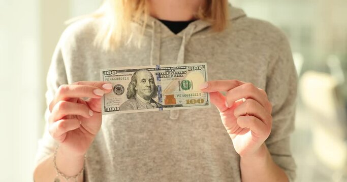 Closeup of woman hands holding 100 dollar bill against blurred background