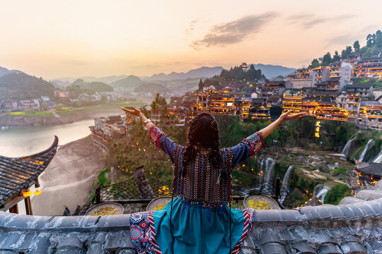 Young female tourist in traditional dress looking at the beautiful landscape at the Furong old Town, The famous tourist destination at Hunan Province, China