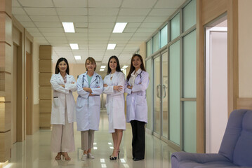 Portrait group of attractive four woman doctor in white coat standing with arm across together in hospital corridor. - 773709686