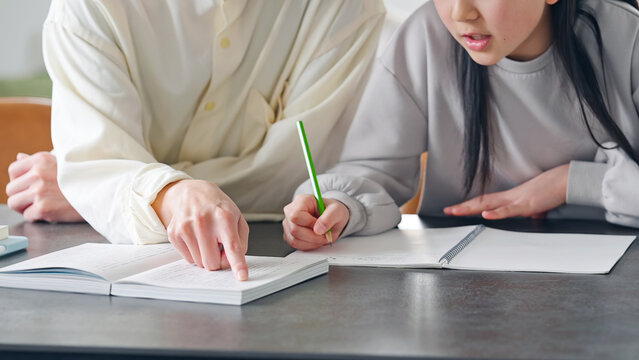 A girl being taught to study by a man at a desk.