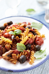Baked pasta with cherry tomatoes, olives and mozzarella cheese. Bright wooden background. Close up.	