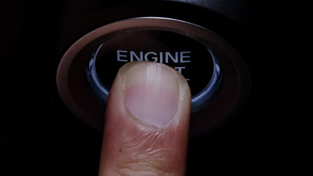 The driver's hand is pressing the car start button. Concept of transportation and technology	