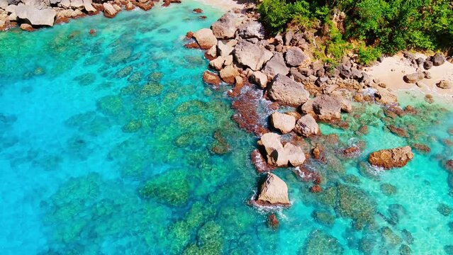 Aerial view of the Cote d'Azur of the Caribbean Sea with a wild beach. Crystal clear turquoise ocean waves on rocks and sand. Wildlife seascape, top view. Summer and spring holidays.